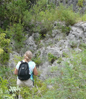 Person wearing a backpack, walking outside along a trail